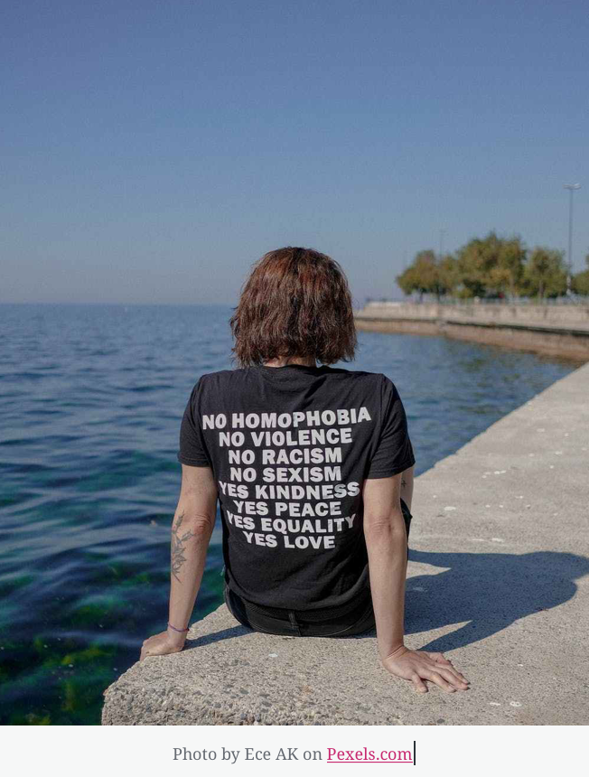 Person sitting by water with message t-shirt