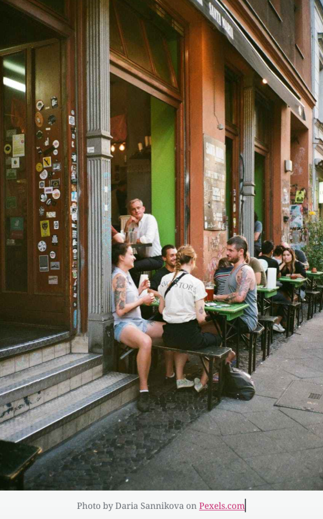 Sidewalk cafe a group gathered around is talking